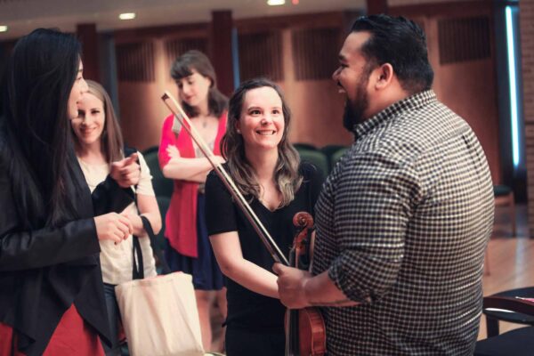 Violin faculty laughing with students